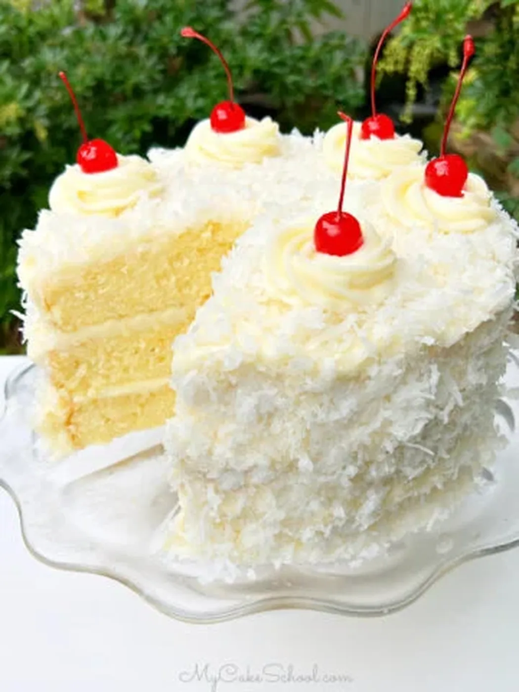 Sliced Pina Colada Cake on a glass pedestal.؛ کیک پاند بادام و Raspberry