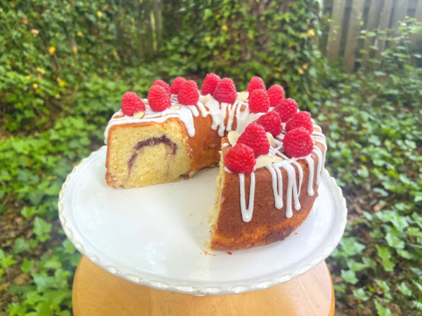 Raspberry Almond Layer Cake, sliced, on a cake pedestal.؛ کیک پاند بادام و Raspberry